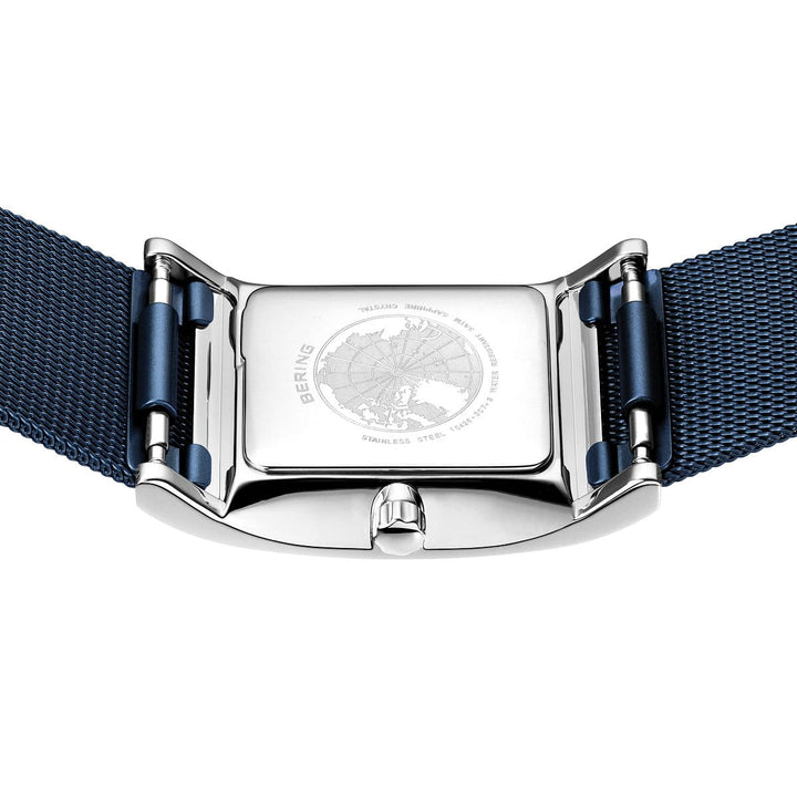 Close-up van de achterkant van een zilveren Bering dameshorloge (model 10426-307-S) met een blauwe mesh band. De roestvrijstalen kast, geëtst met een wereldkaart, complementeert het krasbestendige saffierglas en quartz uurwerk bevestigd met stevige scharnieren.