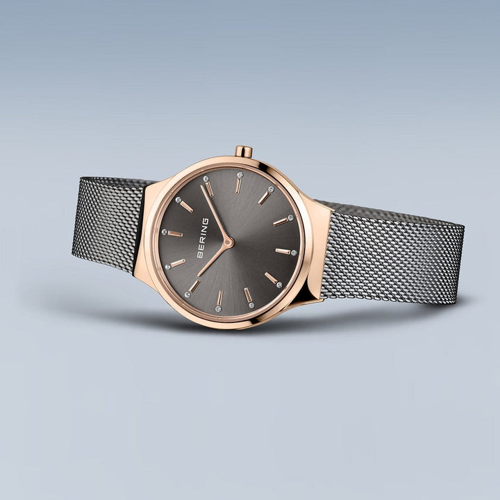 Het Bering polshorloge, model 12131-339-GWP, heeft een roségouden kast en Milanese band. De donkergrijze wijzerplaat heeft minimalistische markeringen en wijzers, aangestuurd door Quartz-uurwerk voor precisie.