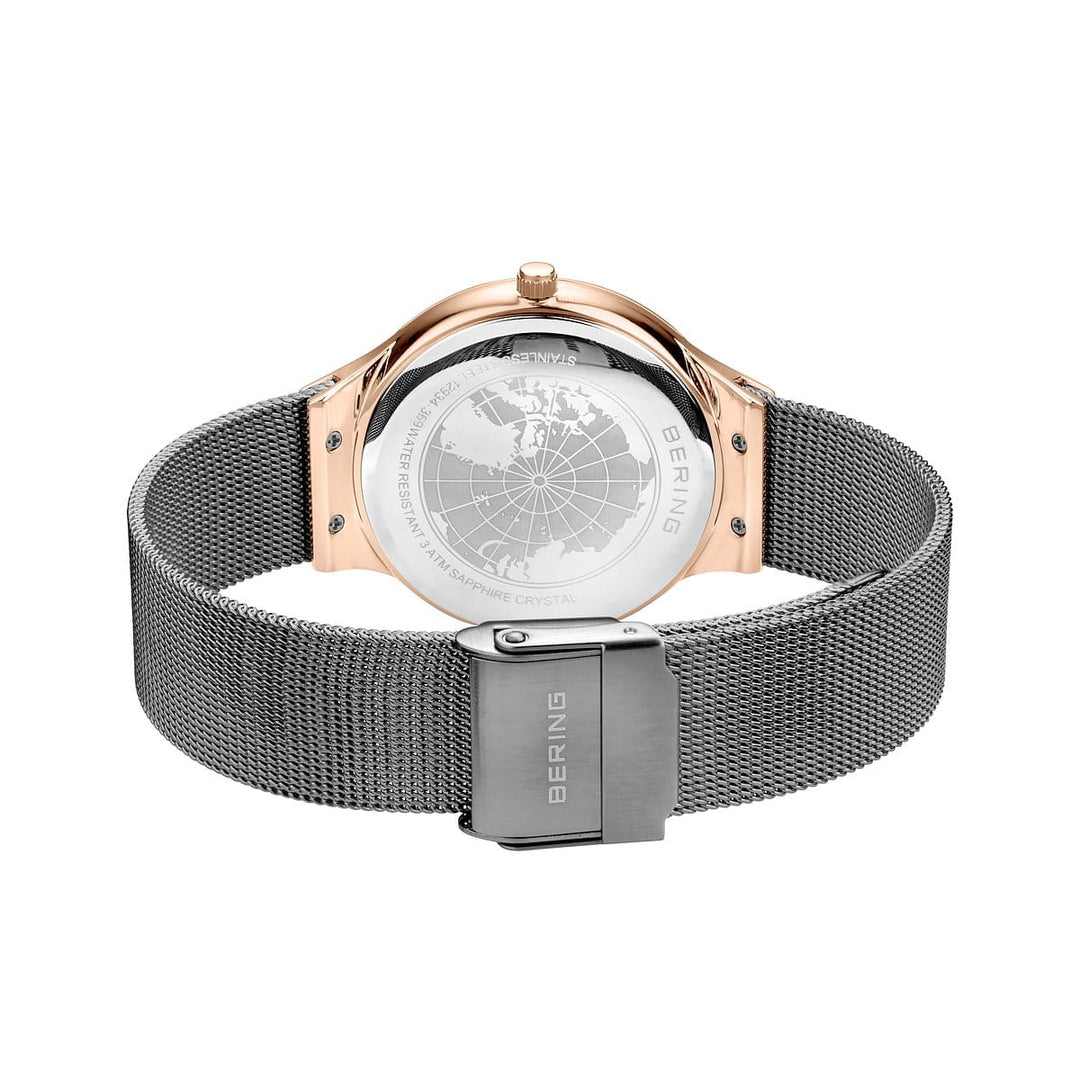 De afbeelding toont het elegante horloge van een Bering dameshorloge, model 12934-369, met een zilveren meshband en roségouden kast. Een wereldkaartgravure siert de achterkant en de sluiting is voorzien van de Bering-signatuur.