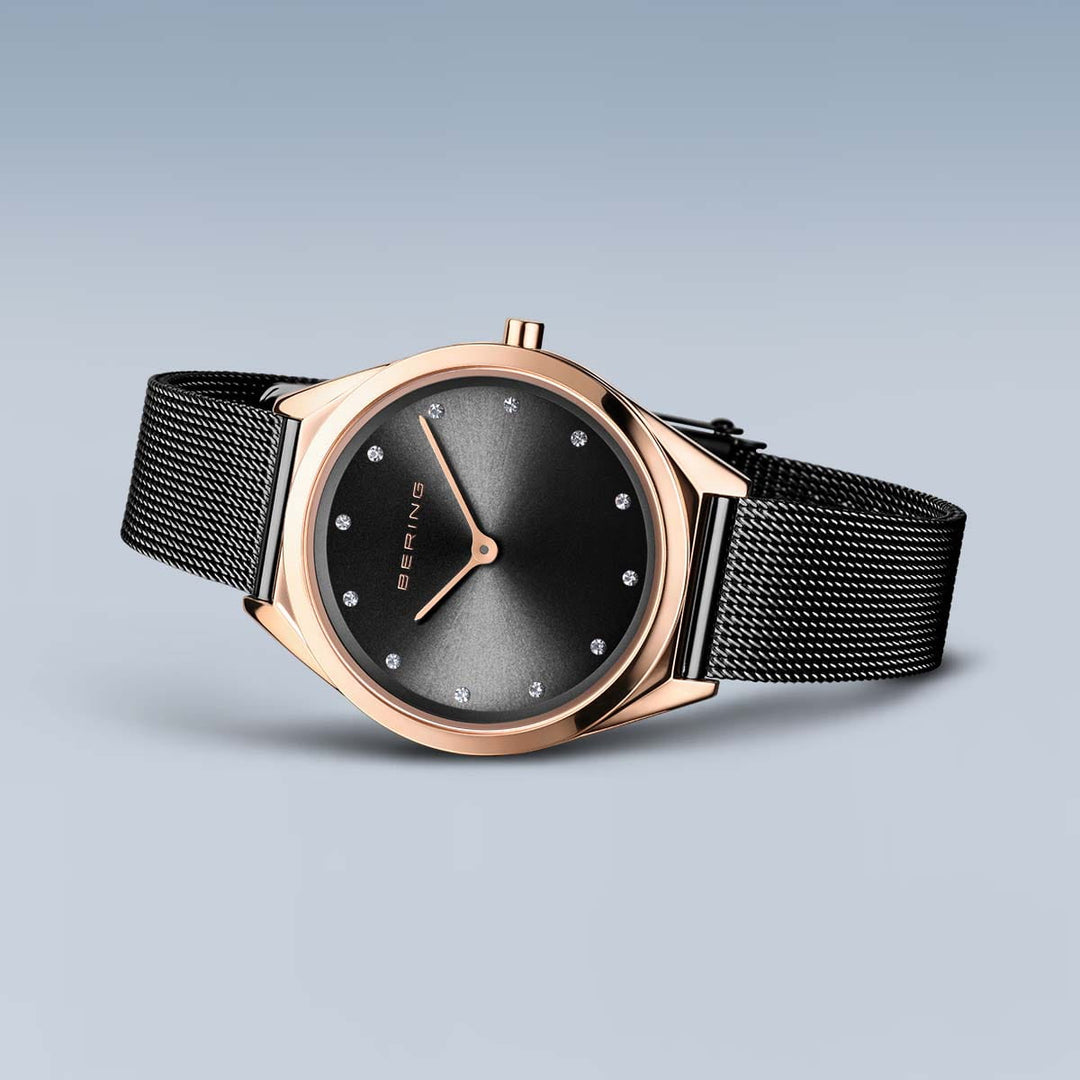 De Bering 17031-162 is een strak quartzhorloge met een roségouden kast, zwarte meshband, krasbestendig saffierglas, minimalistische uurmarkeringen en twee wijzers. De merknaam Bering siert de wijzerplaat tegen een zachte gradiëntachtergrond.