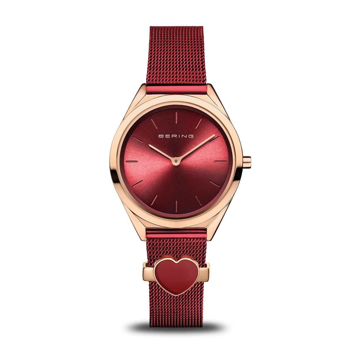 Montre avec un cadran rouge, boîtier doré rose et bracelet en maille rouge, décoré d'un cœur.