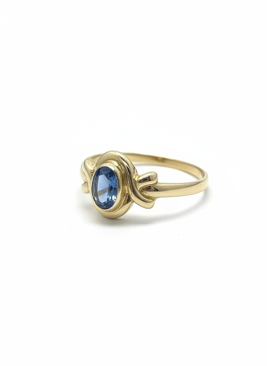 Bague vintage en or 14 carats avec un topaze bleu, design noué.