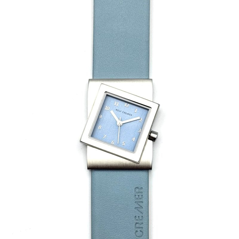 Montre carrée avec cadran bleu clair, boîtier en acier inoxydable et bracelet en silicone bleu.