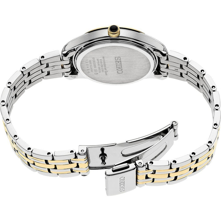 De afbeelding toont de achterkant van een Seiko dameshorloge SWR070P1 met een two-tone zilveren en gouden roestvrijstalen band. De sluiting is gedeeltelijk open, met tekst op de achterkant van de kast, terwijl rechthoekige schakels elegant met elkaar zijn verbonden.
