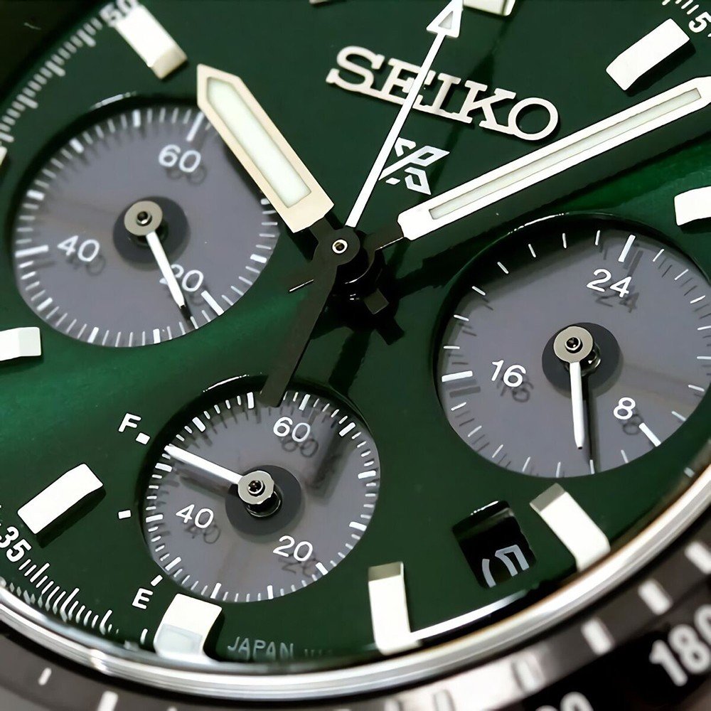Close-up van de Seiko Prospex SSC933P1 herenhorloge face, met een groene wijzerplaat met drie subdials en een datumvenster. Witte wijzers en indexen steken af tegen de groene achtergrond. Hoofdwijzers geven de tijd aan, subdials bieden chronograaffuncties voor seconden, minuten en 24-uurstijd.