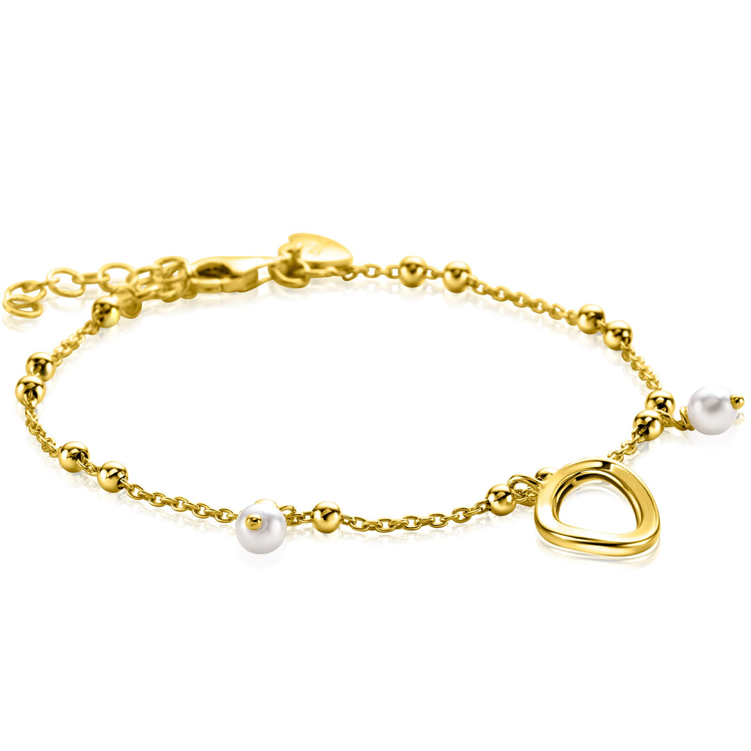 De Zinzi Armband Gold Plated Zia2405 is een delicate armband met kleine ronde kralen, twee witte hangende parels en een hartvormige bedel. Het heeft een verstelbare ketting met een sluiting en wordt elegant weergegeven op een witte achtergrond.