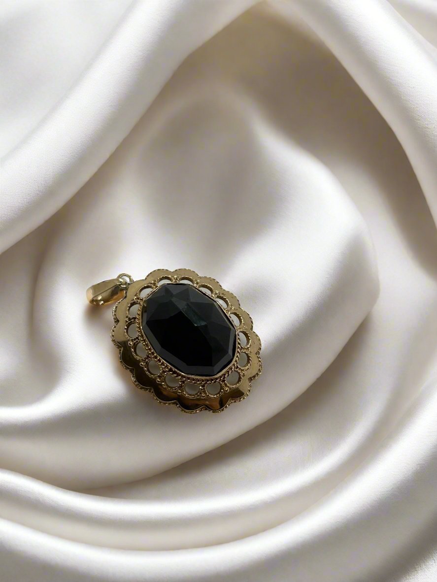 Pendentif vintage en or 14k avec un grenat noir, décoré de motifs en relief.