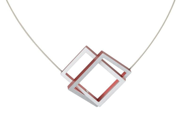Collier avec deux rectangles imbriqués, l'un rouge et l'autre argenté, sur un cordon fin.