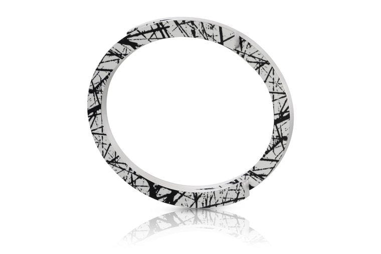 Bracelet jonc blanc avec motifs noirs abstraits.