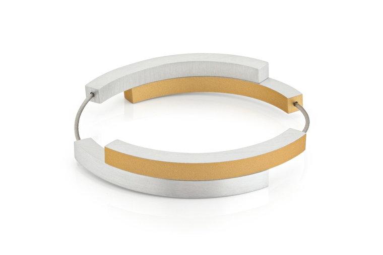 De Armband Vier bogen Goud|Geel A32G van CLIC Creations is een strakke, moderne armband die met de hand in Nederland wordt gemaakt. De armband is voorzien van afwisselend zilveren en gouden rechthoekige staafjes op een dunne, flexibele draad voor een minimalistische en stijlvolle look.