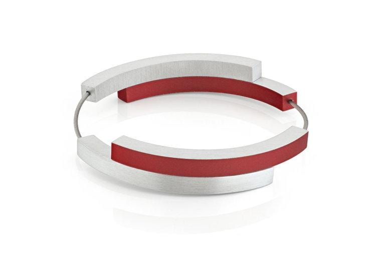 Bracelet argenté avec quatre arcs, deux en rouge et deux en métal.
