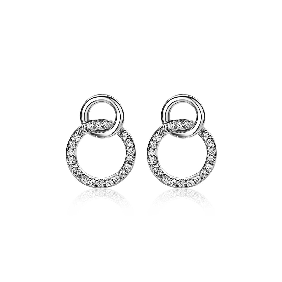 De Zinzi Oorbellen Zilver Zio1782 van Zinzi zijn zilveren oorbellen met twee in elkaar grijpende cirkels: één met fonkelende steentjes en één gepolijst, afgebeeld op een witte achtergrond.