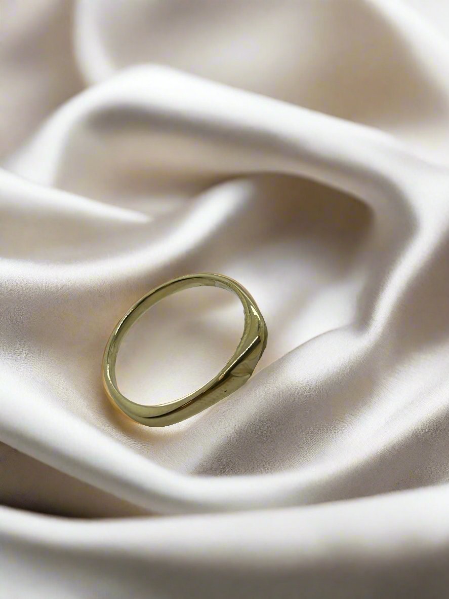 Vintage gouden ring van 14k met een eenvoudige, ronde vorm op een satijnen ondergrond.