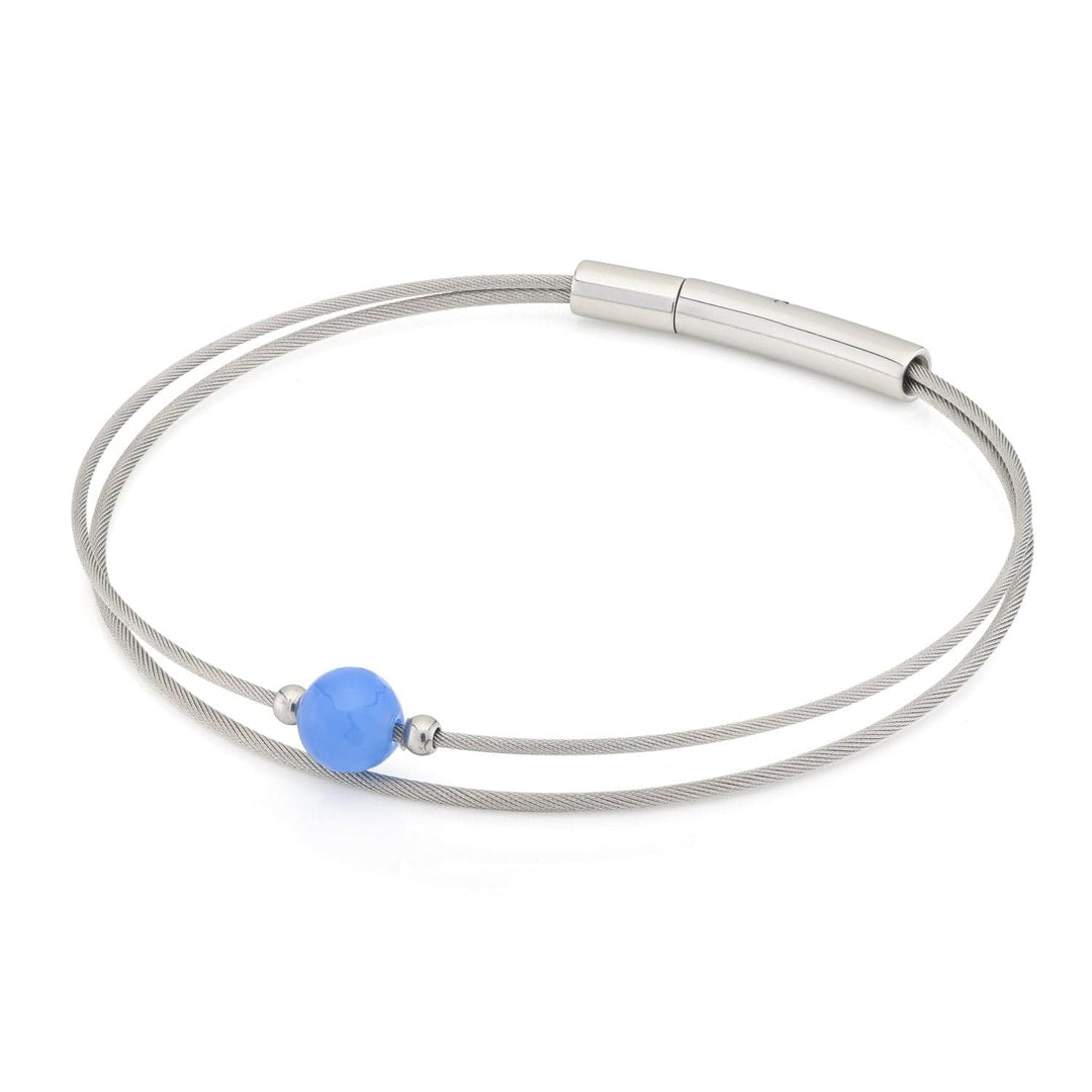 De Thinking of You Armband Agaat A714A van CLIC Creations heeft een minimalistisch ontwerp met een centrale blauwe kraal, twee dunne metalen strengen en een cilindervormige zilveren sluiting: een ideaal cadeau voor elke gelegenheid.