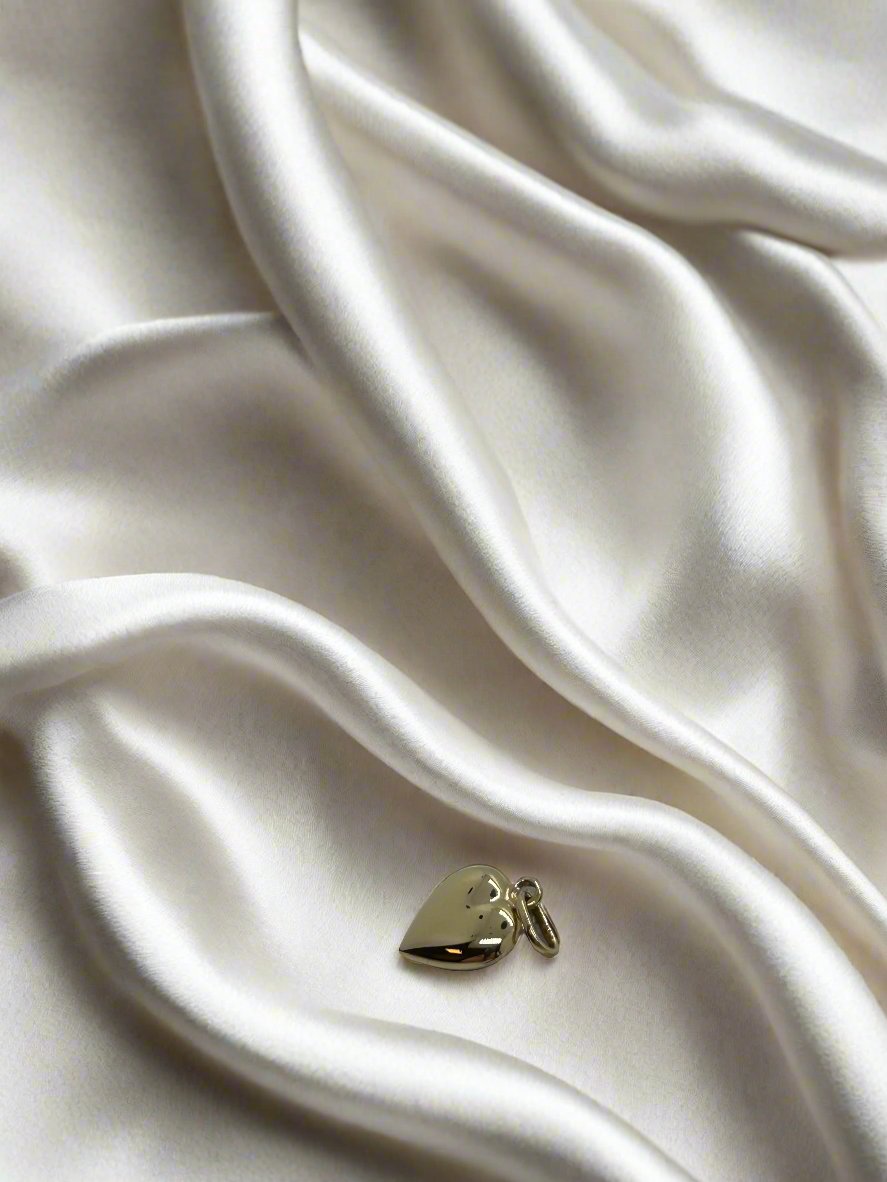 pendentif en cœur en or jaune 14K, léger et brillant, posé sur un tissu satiné.