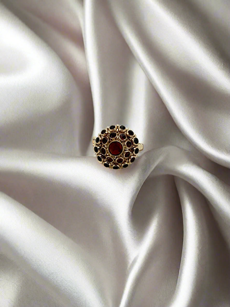 Bague vintage en or 14 carats ornée d'un grenat central et de pierres noires.