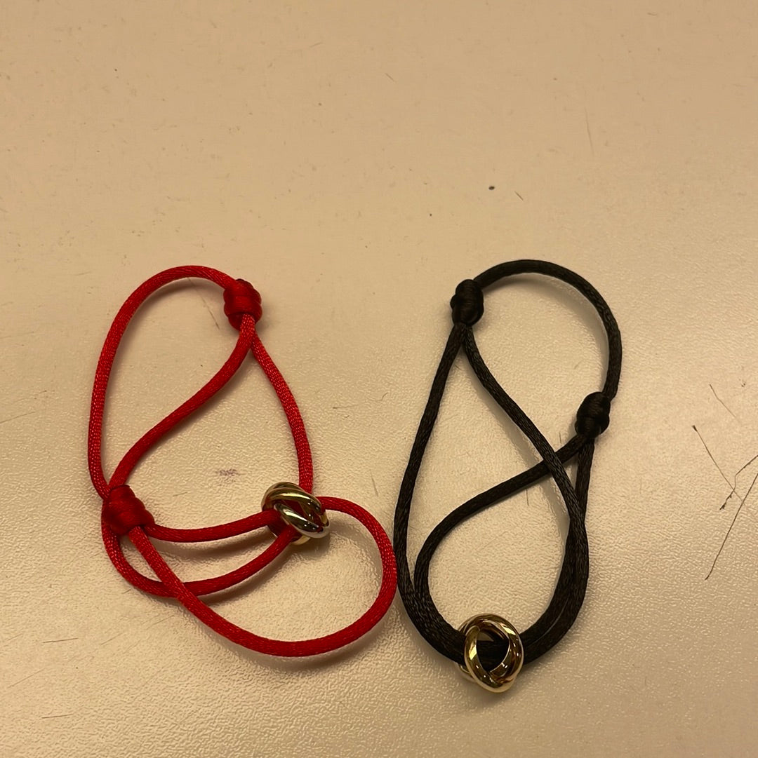 Bracelet en cuir noir et rouge avec un détail en métal doré.