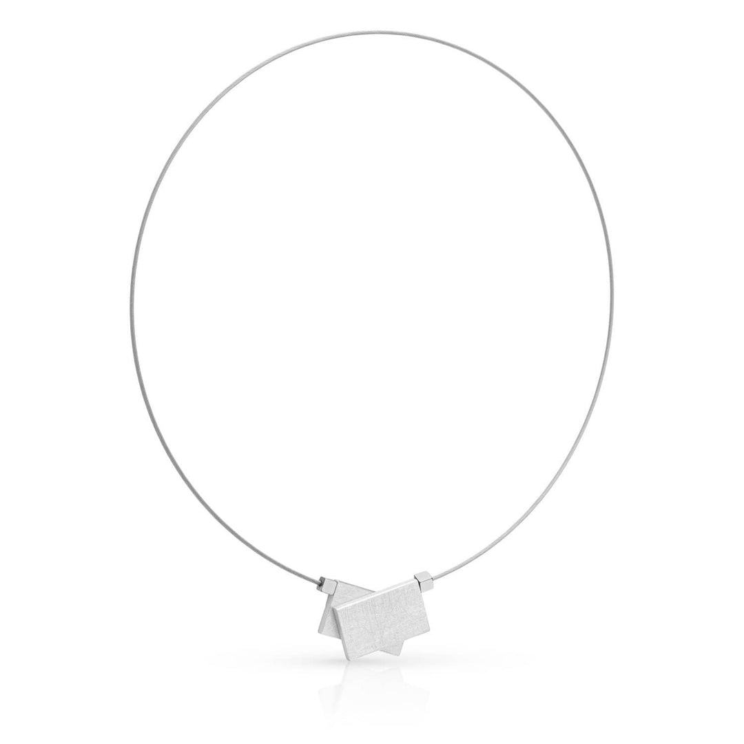 De Collier Gekruiste Rechthoeken & Hematiet C233 van CLIC Creations heeft een minimalistisch zilverkleurig ontwerp met een dunne draad en een geometrische hanger met in elkaar grijpende vormen, aangevuld met een magnetische sluiting voor eenvoud en elegantie.