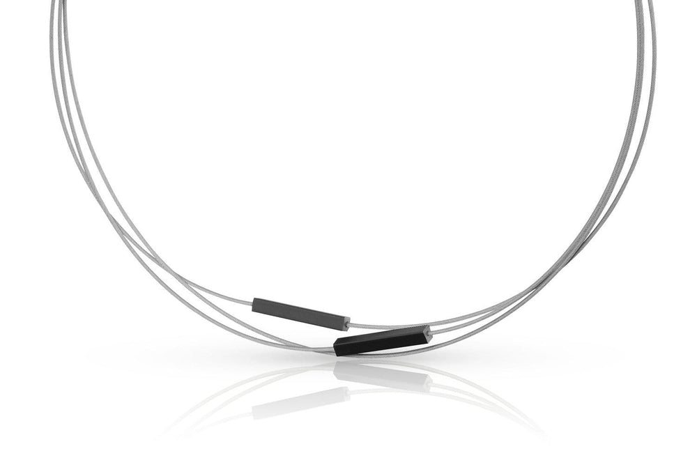 De Collier Staafjes Zwart C243Z van CLIC Creations is een minimalistisch stuk met drie dunne draden met twee kleine rechthoekige zwarte kralen tegen een witte achtergrond. De draden, elegant gebogen voor beweging, zijn versterkt met een edelstalen bajonetsluiting.