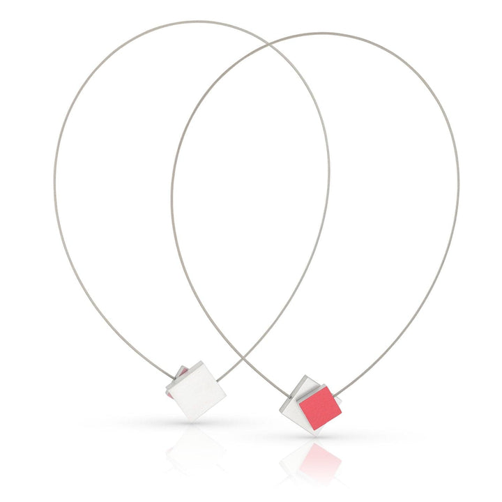 CLIC Creations Collier Vierkant met gekleurd vierkant C263R bevat twee minimalistische kettingen met draadlussen en centrale kubussen, een rode en een witte. De elegante druppelvormen versterken het geometrische ontwerp, terwijl de magnetische sluiting zorgt voor gemakkelijk dragen. Perfect voor elk stijlvol ensemble.