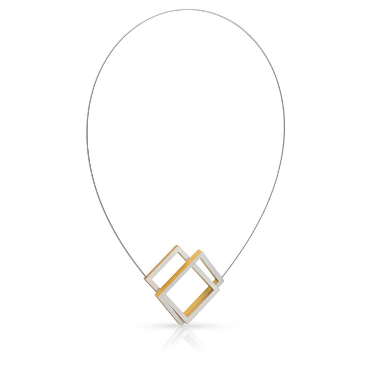 De Collier Twee rechthoeken in elkaar Goud|Geel C30G van CLIC Creations is een geometrische ketting gemaakt in Nederland, bestaande uit twee in elkaar grijpende rechthoekige frames, één van zilver en één van goud, op een dunne gebogen draad, wat een eenvoudige maar toch eigentijdse esthetiek oplevert.