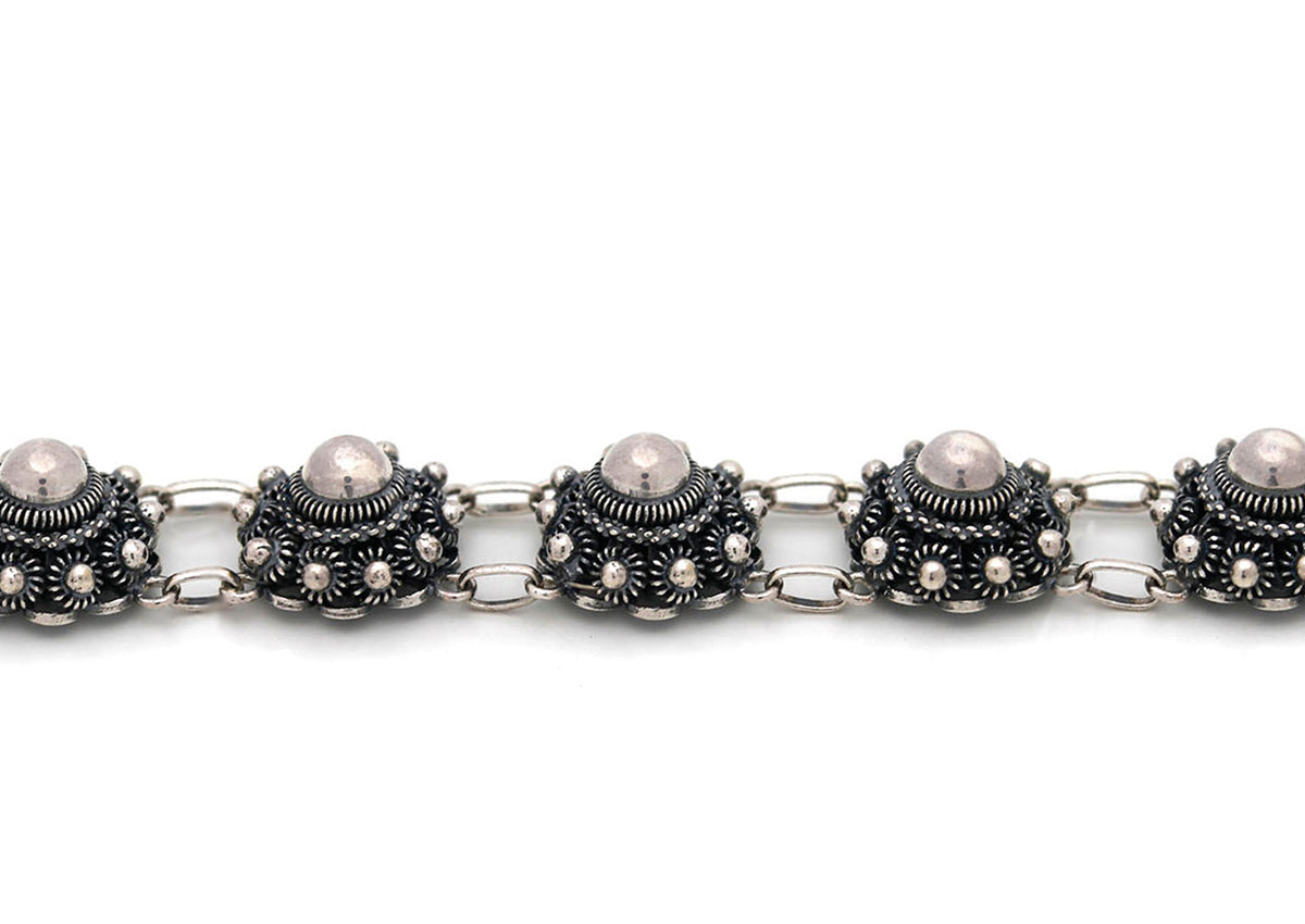 Bracelet en argent avec des motifs de boutons de mer, perles et détails en relief.