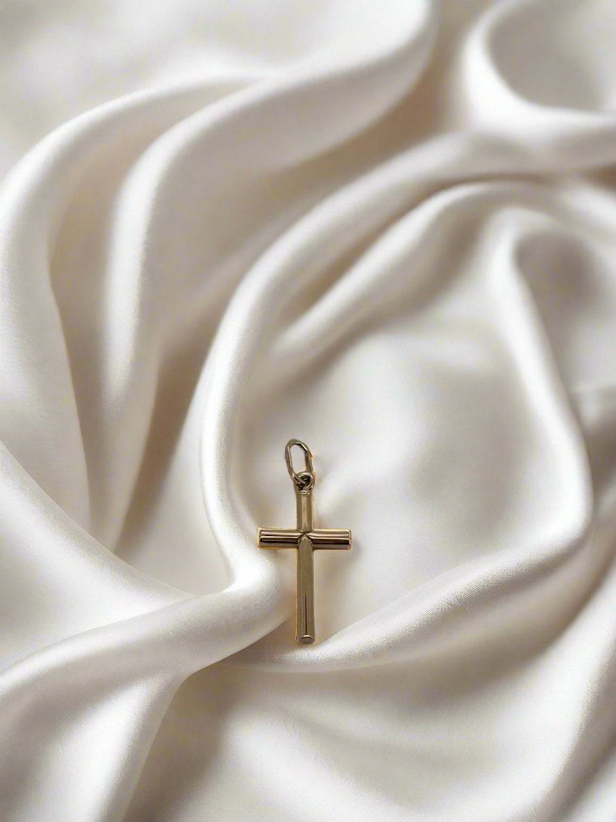 pendentif croix en or rose 14K sur un fond de satin blanc.
