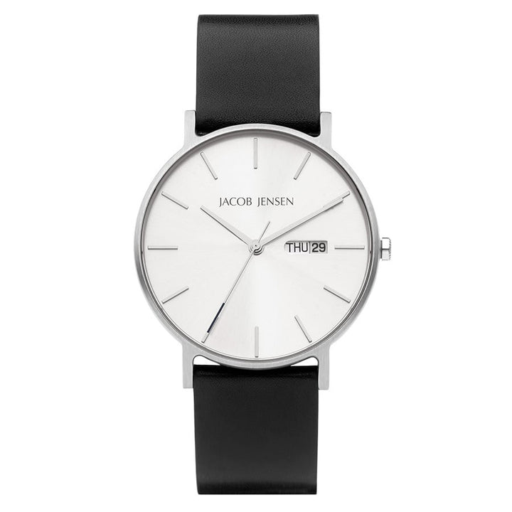De Jacob Jensen 160 is een minimalistisch quartz polshorloge met een witte wijzerplaat met zilveren markeringen en wijzers. Het bevat een klein datumvenster met THU 29, heeft duurzaam saffierglas en is uitgerust met een strakke zwarte leren band.