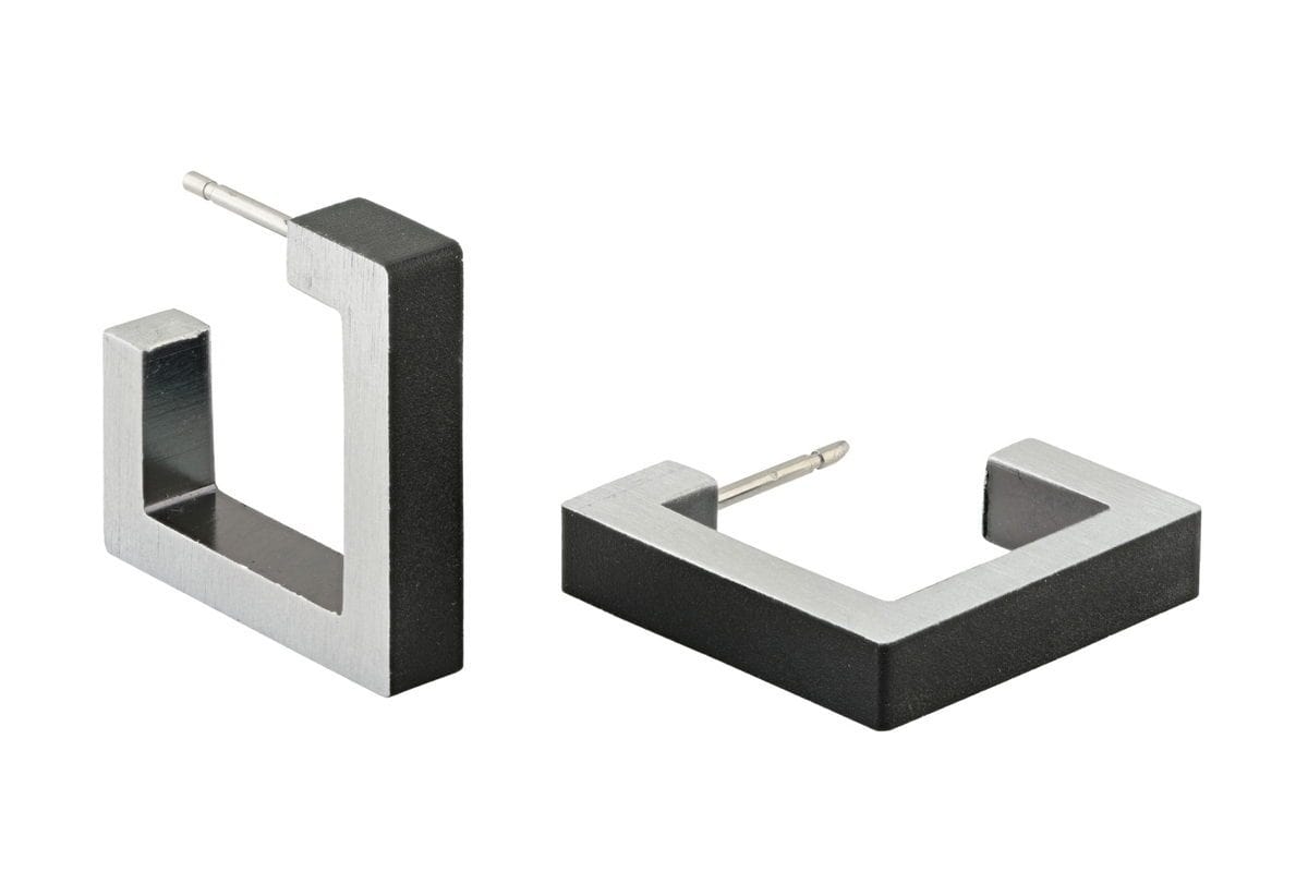 Boucles d'oreilles carrées en métal noir et argenté, avec une finition mate.
