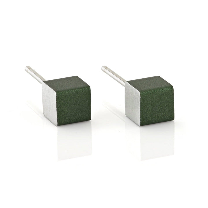 De Oorsieraad Kubusjes Groen O28GR van CLIC Creations zijn kubusvormige zilveren oorbellen met donkergroene vlakken, elegant rustend op een wit reflecterend oppervlak. Handgemaakt in Nederland en hypo-allergisch, ze tonen uniek vakmanschap en stijl.