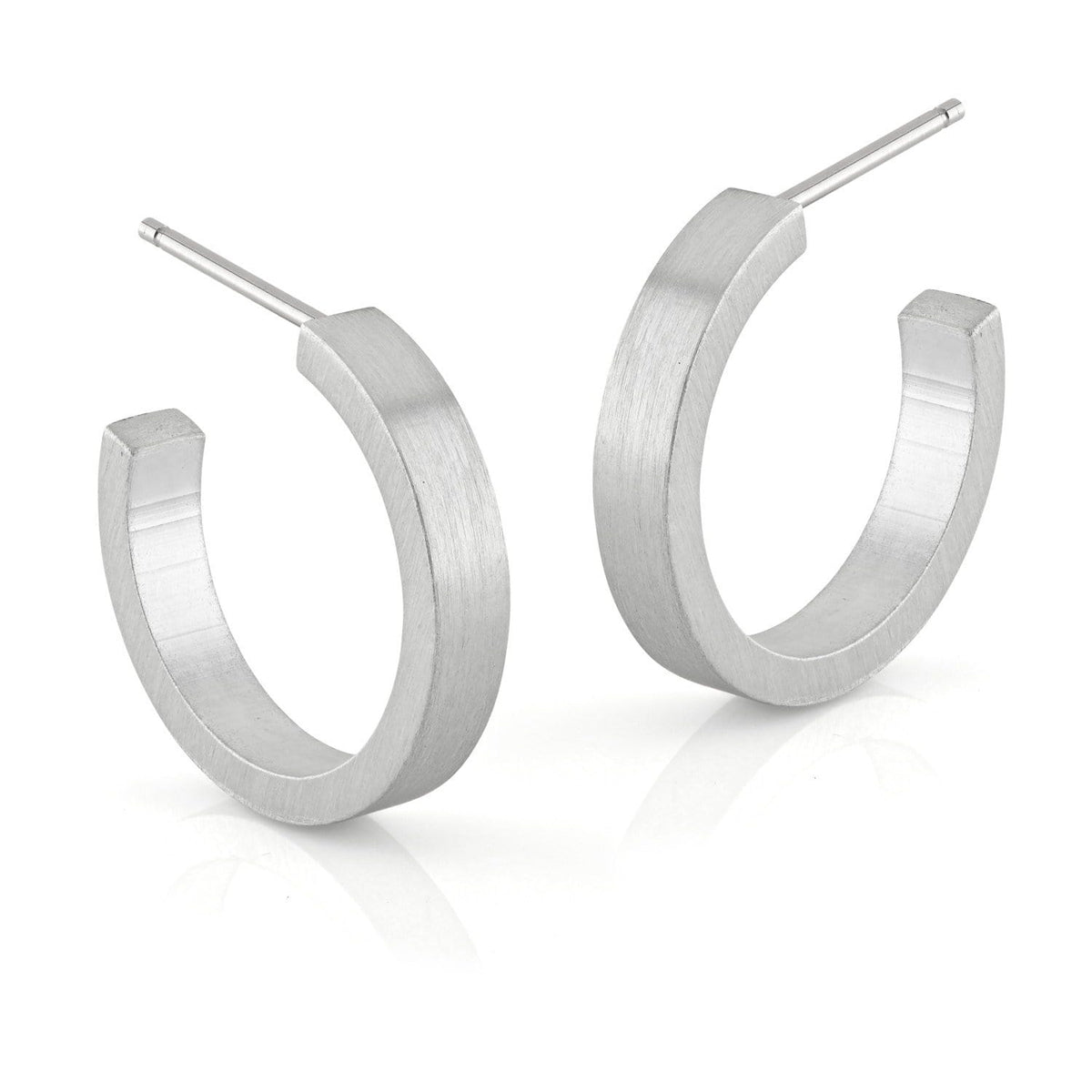 Boucles d'oreilles rondes en métal mat, forme légèrement angulaire.