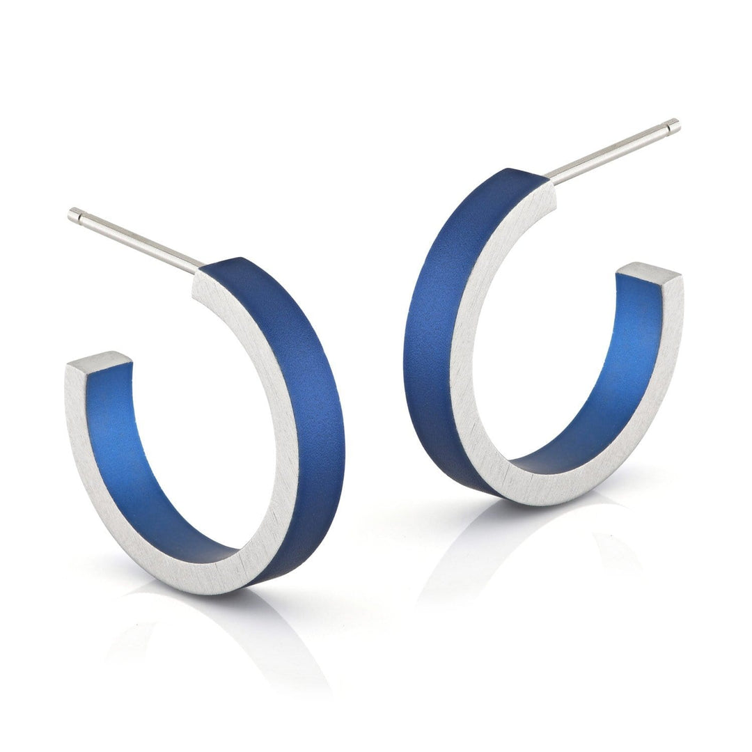 De Creolen Ronde ringetjes Blauw O51B van CLIC Creations zijn uniek ontworpen hypoallergene aluminium oorringen met een zilveren buitenkant en levendig blauwe binnenkant. Deze handgemaakte oorsieraden zijn voorzien van open hoepels en rechte palen, geplaatst tegen een effen witte achtergrond.