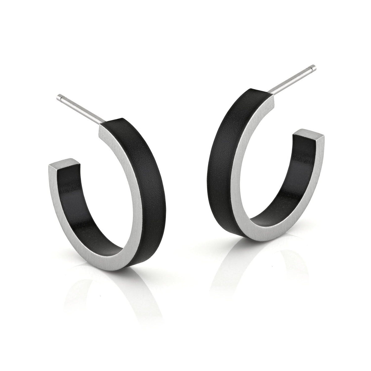 Boucles d'oreilles rondes en métal argenté avec un détail noir.