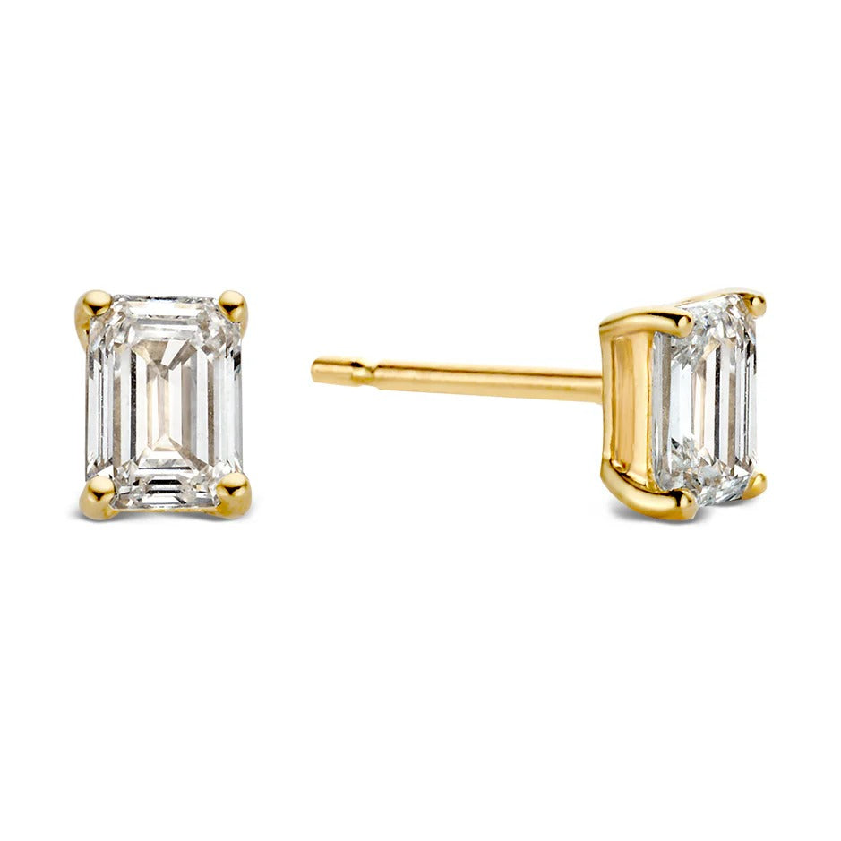 De Oorstekers Nora 0,50 crt. geelgoud van Aurore Jewelry zijn voorzien van rechthoekige smaragdgroene diamanten in een zetting van geel goud met vier pootjes, zowel van voren als van opzij bekeken.