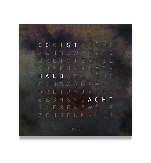 Horloge mural Qlocktwo en fer brut avec chiffres en lettres, affichage en noir et blanc.