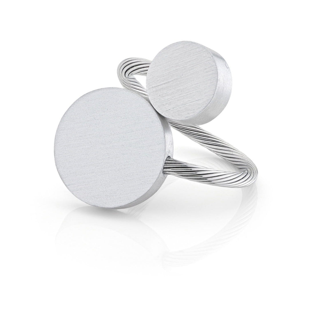 De Ring Twee ronde vormen R5 van CLIC Creations is een zilveren ring die met de hand is gemaakt in Nederland, met twee unieke, ronde platte schijven van verschillende groottes. De grotere schijf staat centraal met een kleinere erboven, aangevuld met een getextureerde gedraaide band voor een moderne minimalistische look.