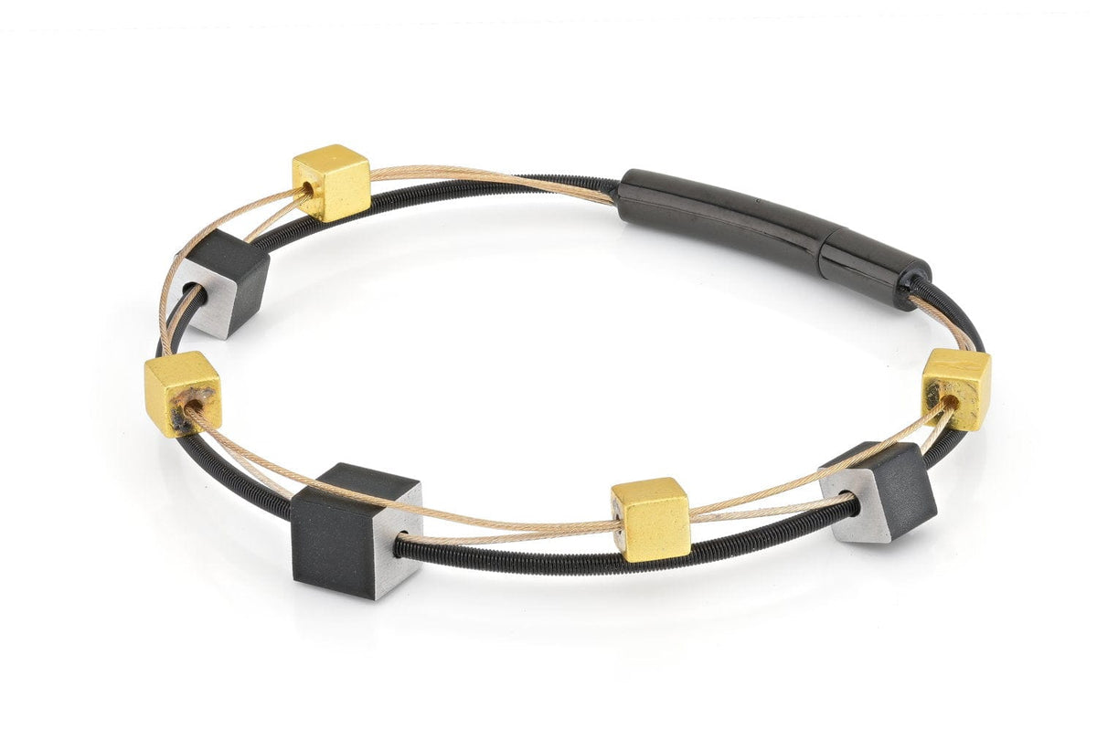Bracelet en métal doré et noir avec des cubes ludiques en alternance.