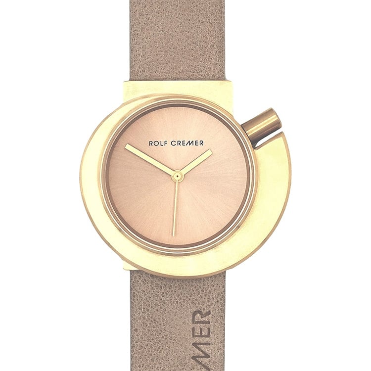 Montre Rolf Cremer avec un cadran doré et un bracelet en cuir beige.