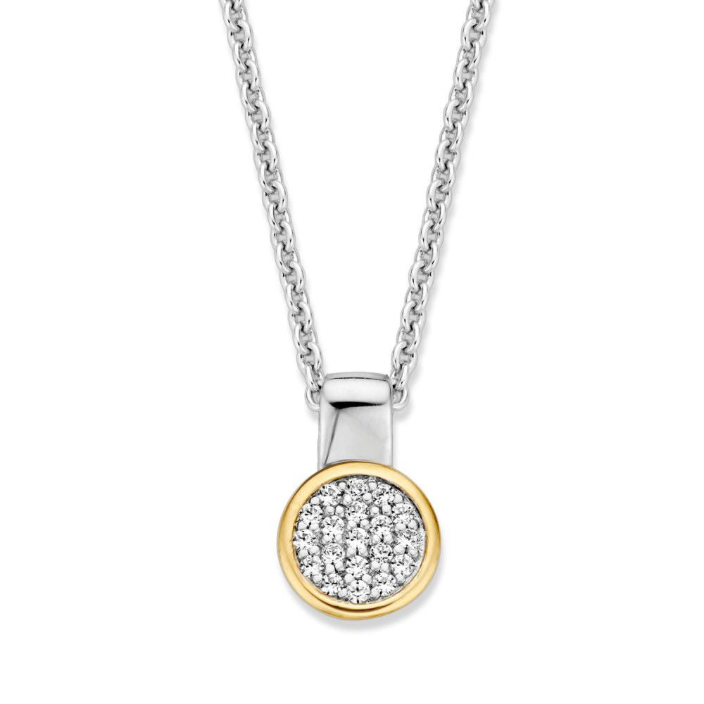 Pendentif argenté avec un cercle doré et des zirconias blancs, suspendu à une chaîne.