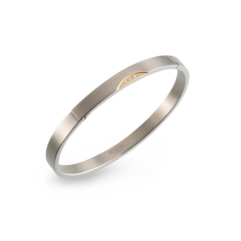 Bracelet en titane bicolore avec un détail doré et trois petites pierres.