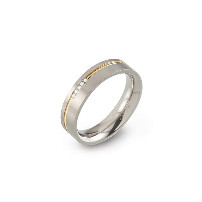 Bague en titane bicolore avec une ligne dorée et trois petites pierres brillantes.