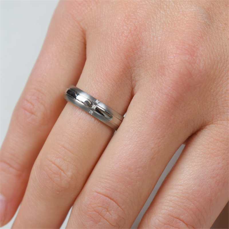 Een close-up van een hand met korte, ongelakte nagels, met de Boccia Titanium Ring dia 3/0.015 - 0131-03 van Boccia. De ringvinger is bezet met kleine diamanten en de huid heeft een natuurlijke tint.