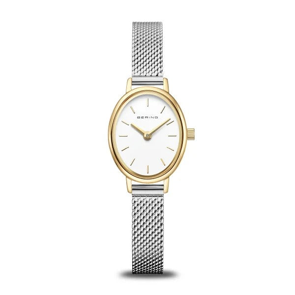 Montre ovale avec boîtier doré, cadran blanc et bracelet en maille argentée.