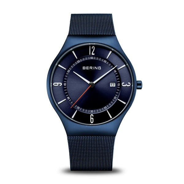 Montre bleue avec un cadran minimaliste, bracelet en maille métallique et affichage de la date.