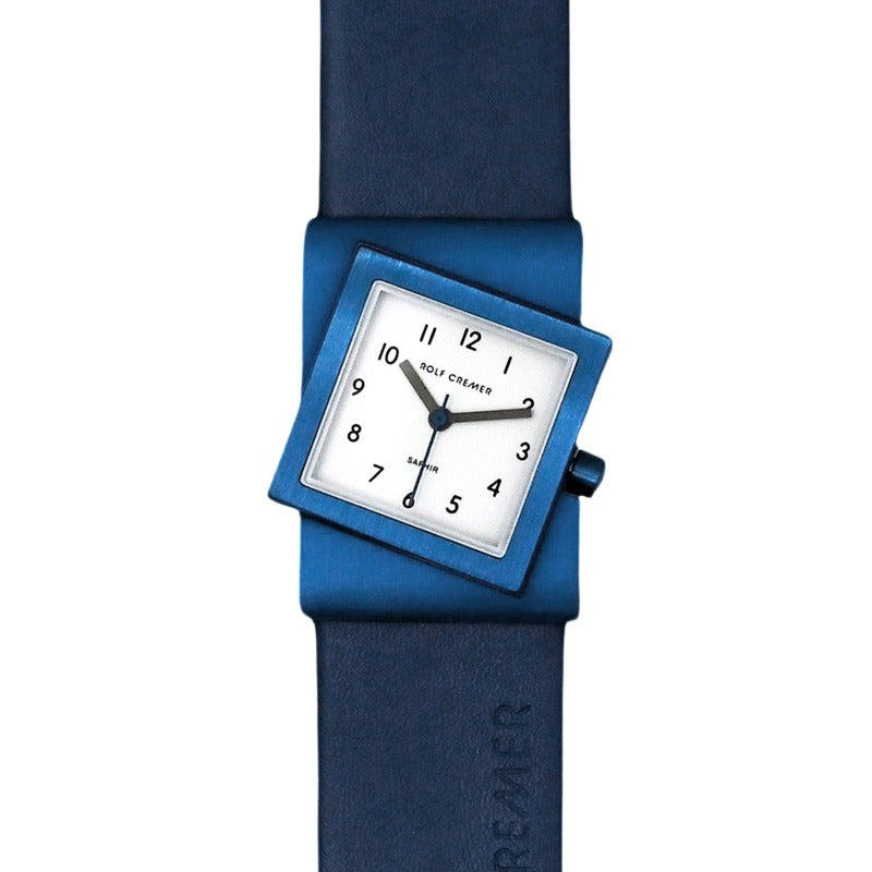Montre carrée bleue avec un cadran blanc et des chiffres noirs, bracelet en silicone.