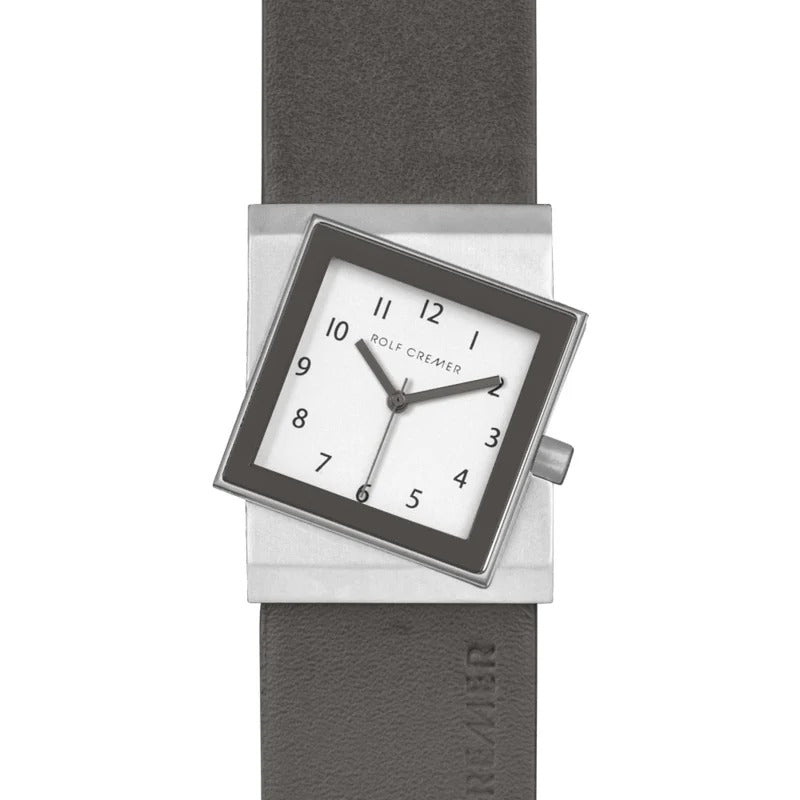 Montre carrée Rolf Cremer avec cadran blanc, chiffres noirs et bracelet en cuir gris.