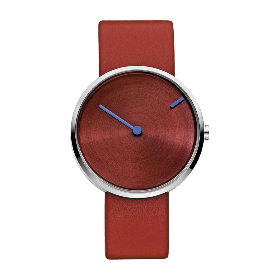 Montre avec un cadran rouge et des aiguilles bleues, bracelet en cuir rouge.