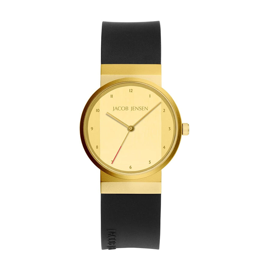 De 745 van Jacob Jensen is een gouden dameshorloge met een zwarte band, voorzien van een minimalistische gouden wijzerplaat, subtiele zwarte uurmarkeringen en wijzers, een opvallende rode secondewijzer en een gegraveerd zwart logo op de band.