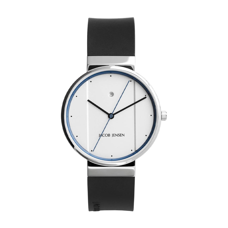 Het Jacob Jensen 750 horloge is een minimalistisch horloge met een roestvrijstalen kast en een strakke zwarte rubberen band. Het heeft een witte wijzerplaat met dunne zwarte uur- en minutenwijzers, een slanke blauwe secondewijzer, kleine zwarte indexen en een datumvenster op 12 uur.