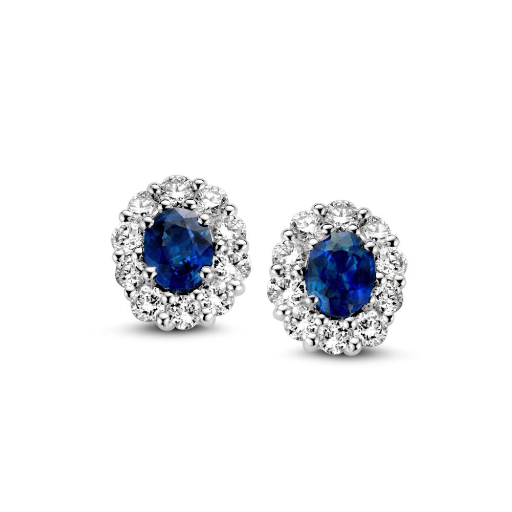 Boucles d'oreilles en or blanc avec saphir et diamants, forme ovale entourée de pierres brillantes.